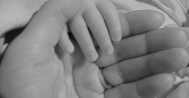 mother holding baby hands at home