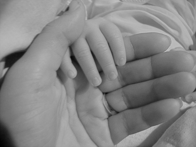 mother holding baby hands at home