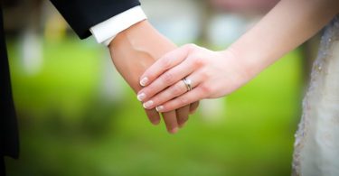 Young married couple holding hands, ceremony wedding day