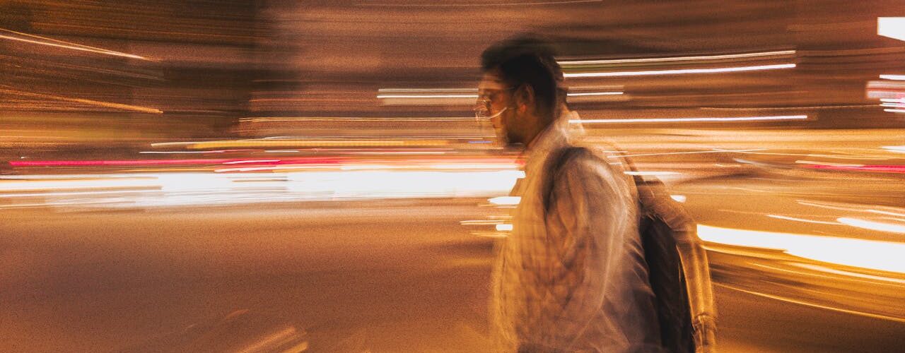 man walking with bag in the middle of lights to depict exist