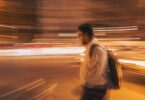 man walking with bag in the middle of lights to depict exist