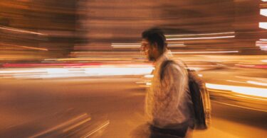 man walking with bag in the middle of lights to depict exist