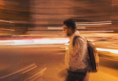 man walking with bag in the middle of lights to depict exist
